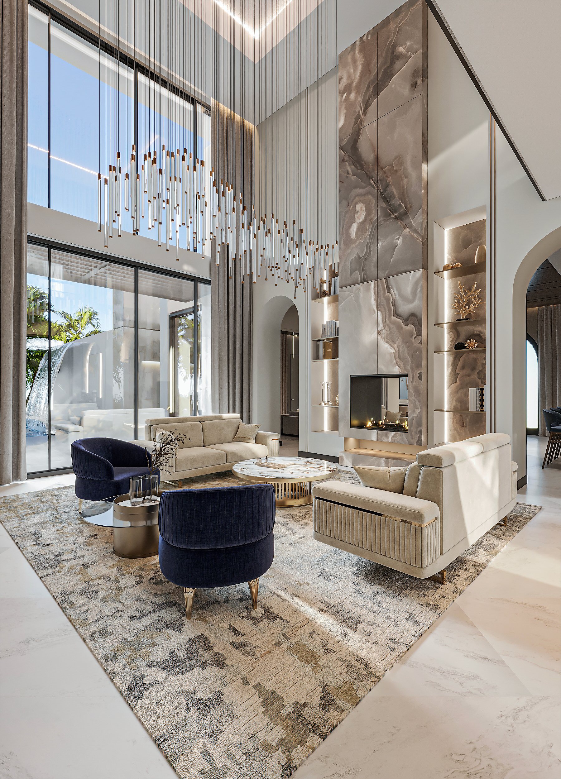 Double-height living room with a tall stone fireplace, suspended lights and curved seating.